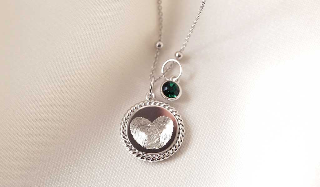 Personalisierter Schmuck: Zwei Fingerabdrücke, die gemeinsam ein Herz bilden als Anhänger einer Kette