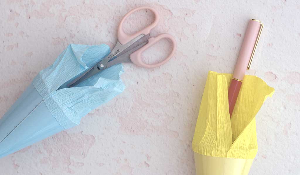 zwei kleine Schultüten mit Mini-Schere und Kugelschreiber als Geschenk zur Einschulung